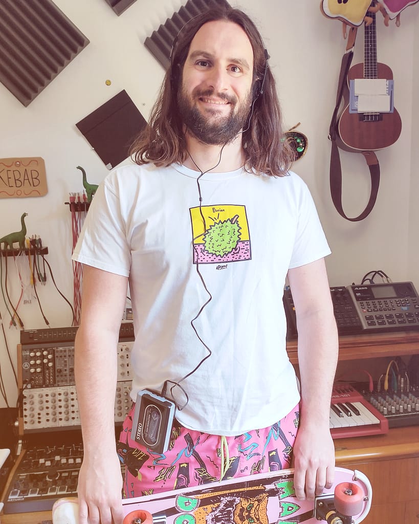 Mattia Molinelli poses in his studio, wearing '90 apparel. The "Magnetic Field" track by Grøntsager delivers a powerful Big Beat electronic sound, contaminated by techno and dubstep. theDustRealm Music
